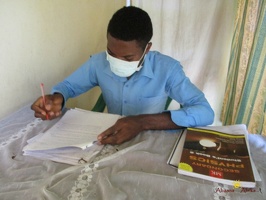 Teacher Bwambale Gordwin marking his students home study work (1)