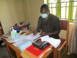 Teacher Irumba Deogracious marking his students homestudy work (1)